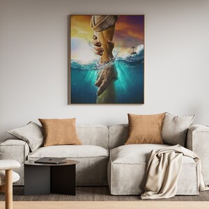 May include: A painting of a hand reaching out from the water to another hand. The painting is framed in a gold frame and is hanging on a wall in a living room.