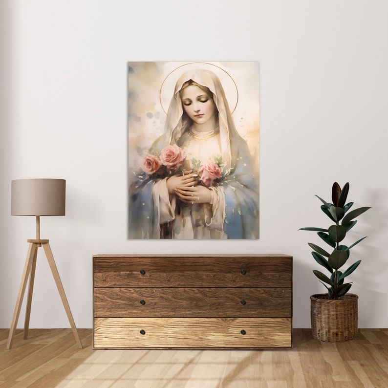 Pode incluir: Uma pintura da Virgem Maria segurando um buqu&ecirc; de rosas cor-de-rosa. Ela est&aacute; vestindo uma t&uacute;nica azul e um v&eacute;u branco. O fundo &eacute; uma suave lavagem de aquarela em azul e branco.