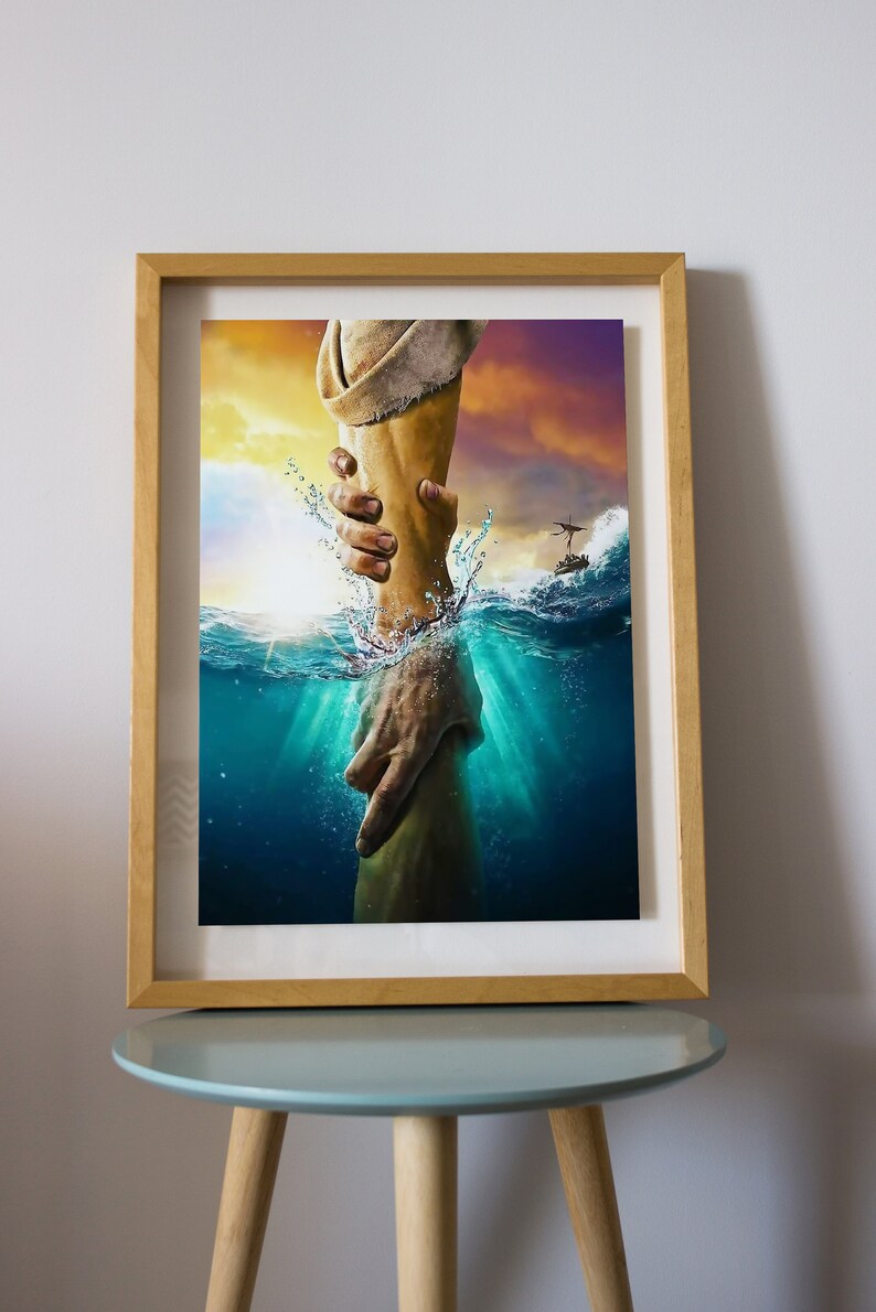 May include: A painting of a hand reaching out from the water to grasp another hand. The water is a vibrant blue and green, and the sky is a soft orange and purple. The painting is framed in a light wood frame.