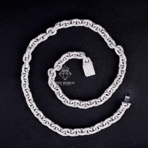 May include: A silver-toned chain necklace featuring oval-shaped links entirely encrusted with small, clear, sparkling stones. The necklace includes a rectangular box clasp closure and displays the text 925 WORLD KING OF JEWELRY in the center.