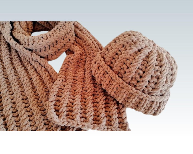 Pode incluir: Um conjunto de cachecol e gorro de malha numa cor bege neutra e quente. O cachecol &eacute; longo e largo, com uma malha espessa e texturizada. O gorro &eacute; de estilo justo, tamb&eacute;m com uma malha texturizada. O conjunto &eacute; feito de um fio macio e grosso.