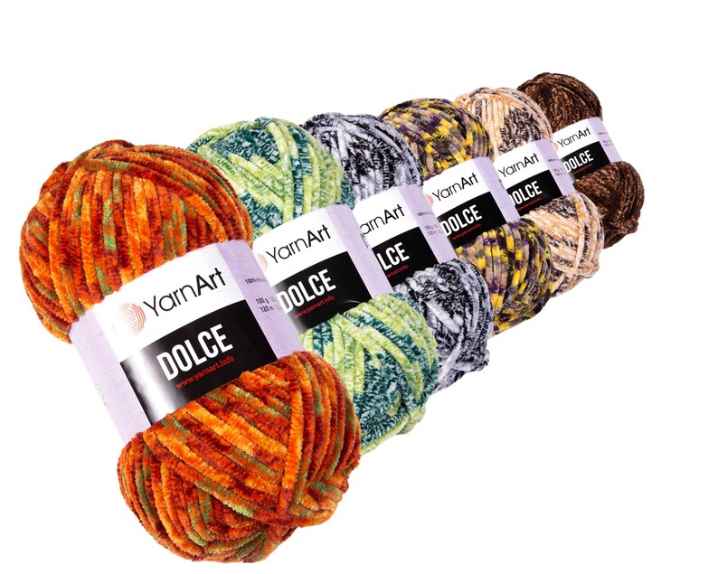 May include: A selection of YarnArt Dolce yarn skeins in a range of colours. The yarn has a soft, velvety texture and comes in shades of orange, green, grey, yellow, and brown. Each skein is labelled with the word "DOLCE".