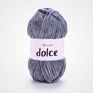 May include: A ball of grey YarnArt Dolce yarn. The yarn has a soft, velvety texture, and the label features the word "dolce". This yarn is suitable for knitting and crochet projects.