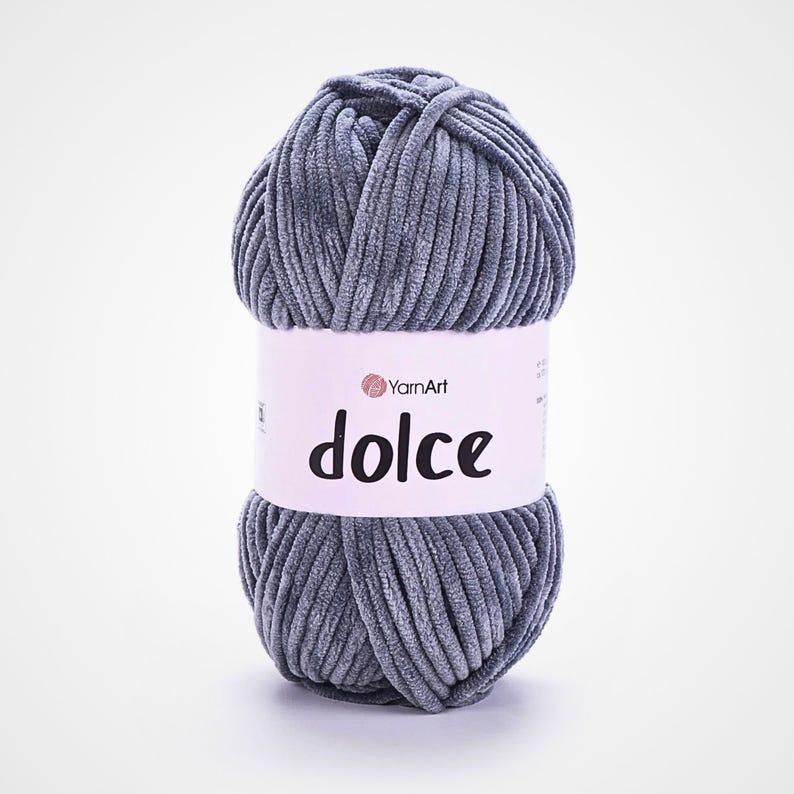May include: A ball of grey YarnArt Dolce yarn. The yarn has a soft, velvety texture, and the label features the word "dolce". This yarn is suitable for knitting and crochet projects.