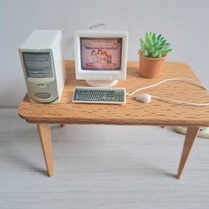 May include: Miniature computer setup on a wooden desk. The setup includes a white computer tower, monitor displaying "Welcome to Lundby!", keyboard, mouse, and a small potted succulent. The desk has four legs.