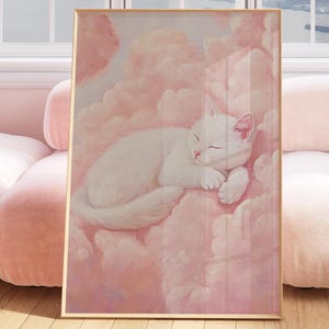 May include: A pink and white painting of a white cat sleeping on pink clouds. The painting is framed in a gold frame and is hanging on a wall in a room with a pink sofa.