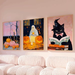 May include: Three framed Halloween-themed paintings on a pink wall above a white modular sofa. The paintings feature a ghost, pumpkins, and a black cat wearing a witch's hat and reading a book.