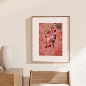 May include: A pink bat hanging upside down from a branch with red berries. The bat is in front of a pink and red floral patterned background.