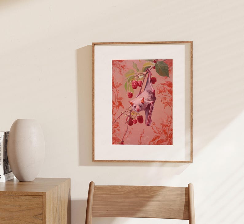 May include: A pink bat hanging upside down from a branch with red berries. The bat is in front of a pink and red floral patterned background.