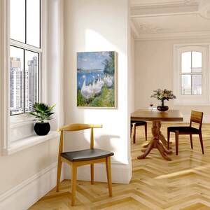 May include: A light wood dining table with a dark wood top and a single chair. The table has a pedestal base and the chair has a curved back and a black seat. The room has white walls and a painting of geese on the wall.