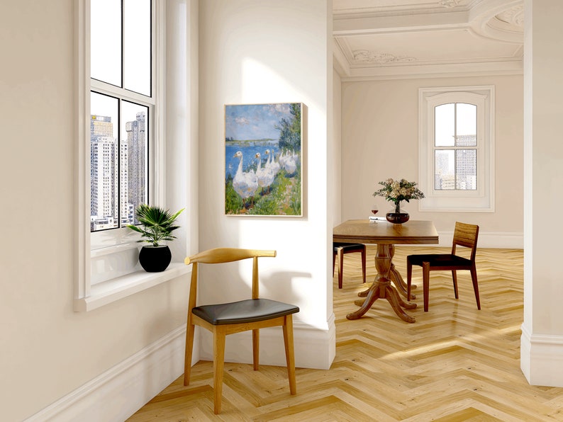 May include: A light wood dining table with a dark wood top and a single chair. The table has a pedestal base and the chair has a curved back and a black seat. The room has white walls and a painting of geese on the wall.