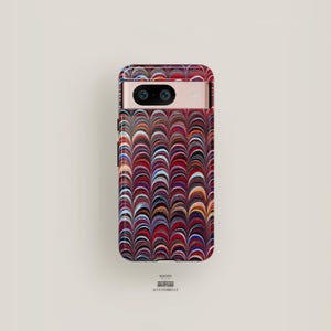 Può includere: Una custodia per telefono in marmo rosso, blu e bianco con un motivo geometrico. La custodia ha un ritaglio per l'obiettivo della fotocamera.