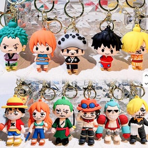 May include: A collection of character keychains featuring various anime figures. Each keychain has a gold-colored ring and a detailed, colorful figurine. The characters have distinct hairstyles and outfits, with a variety of facial expressions.