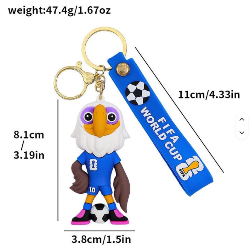 May include: A keychain featuring a cartoon eagle in a blue soccer uniform, holding a soccer ball. The keychain has a blue strap with "FIFA WORLD CUP" text and a soccer ball graphic. The eagle is 3.19 inches tall.