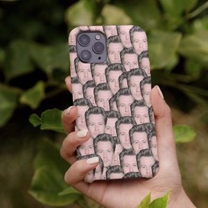 Puede incluir: Una funda de teléfono rosa con un patrón repetido de la cara de un hombre.