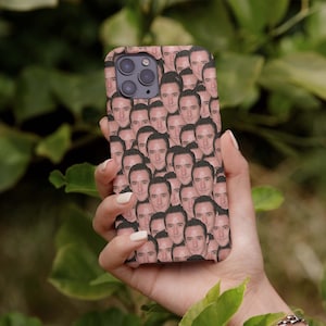 Op de afbeelding: Een telefoonhoesje met een patroon van een herhaald mannengezicht. Het hoesje wordt in een hand gehouden.