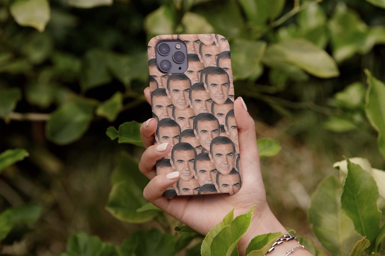 May include: A phone case with a repeated image of a man's face. The case is brown and the man's face is a light skin tone.