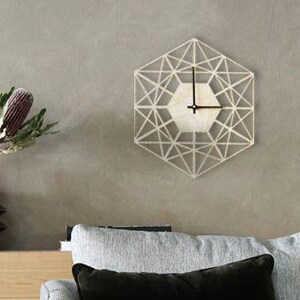 May include: A light grey sofa with two cushions, one black and one grey, sits in front of a wooden cabinet with two doors. The cabinet has a black base and is against a grey wall. A geometric clock hangs on the wall above the cabinet.