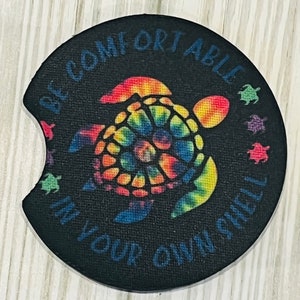 May include: A black round coaster with a tie-dye sea turtle and the text "Be comfortable in your own shell".