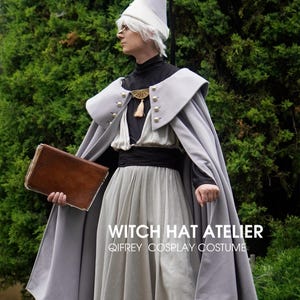 May include: A cosplay costume featuring a light grey pointed hat, a matching grey cape with gold buttons and a gold clasp, a black high-neck top, and a light grey skirt with a black waistband. The text reads WITCH HAT ATELIER QIFREY COSPLAY COSTUME.