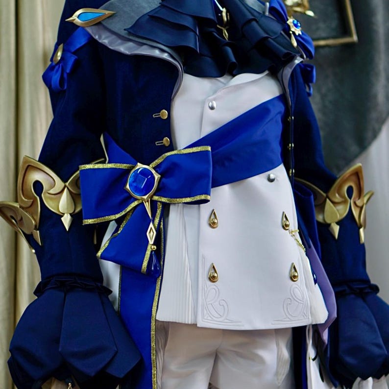 May include: A blue and white costume with a large blue bow and gold accents. The costume features a white jacket with gold buttons and a blue sash.