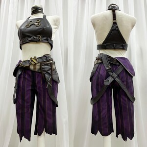 May include: A black leather halter top with gold accents and a matching belt. The top has a criss-cross design on the front. The belt has a buckle with a skull design. The outfit is paired with purple striped pants with black straps and buckles.
