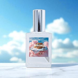 May include: A clear perfume bottle with a silver cap. The label features the text "Heavenly Bread" above an image of a pastry on a plate, set against a pink cloud background. The background is a blue sky with white clouds.