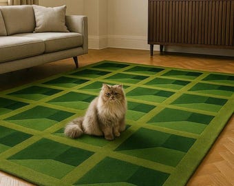 May include: A green geometric patterned rug with a light brown cat sitting on it. The rug features a repeating diamond design in varying shades of green. The cat has long, light brown fur and is looking at the camera. The rug is on a wooden floor.