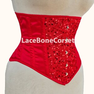 May include: Red satin corset with a panel of red sequins on the right side. The corset has a lace-up back and is made by LaceBoneCorset.