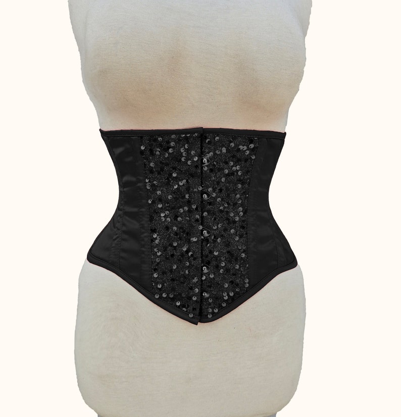 May include: A black satin corset with a decorative design of black sequins.