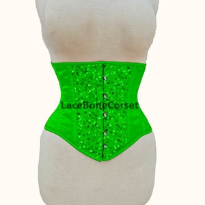 May include: A bright green corset with a satin finish and silver sequins. The corset has a lace-up back and is fastened with hooks and eyes.