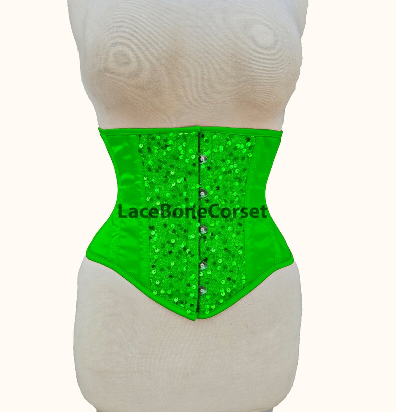 May include: A bright green corset with a satin finish and silver sequins. The corset has a lace-up back and is fastened with hooks and eyes.