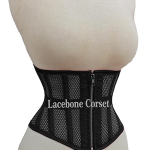 May include: Black corset with vertical panel design and mesh detailing. The corset features a front zipper closure and the text "Lacebone Corset". The garment is displayed on a mannequin.