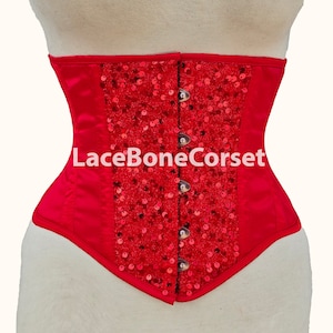 May include: Red satin corset with a red sequin design and a lace-up back. The corset has a metal busk closure and is decorated with the text "LaceBoneCorset".