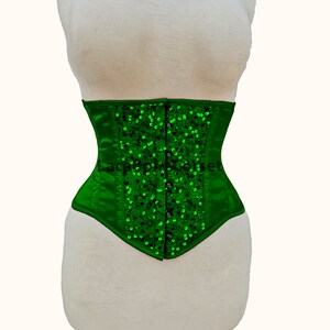 May include: A green satin corset with a pointed bottom and a row of green sequins down the front.