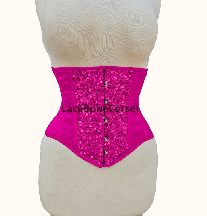 May include: A hot pink satin corset with a decorative design of sequins and silver buttons. The corset has a lace-up back and is a popular choice for special occasions.