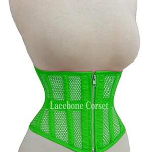 May include: Bright green corset with a mesh and vertical stripe design. The corset has a front zipper closure and the text "Lacebone Corset" is visible. The corset is displayed on a mannequin.
