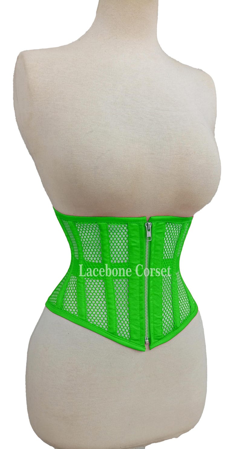 May include: Bright green corset with a mesh and vertical stripe design. The corset has a front zipper closure and the text "Lacebone Corset" is visible. The corset is displayed on a mannequin.