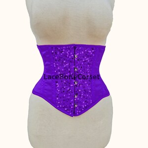 May include: Purple satin corset with a sequined design and a lace-up back. The corset has a boned structure and is designed to cinch the waist.