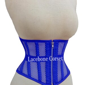 May include: A royal blue corset with a mesh and vertical stripe design. The corset has a silver zipper closure and the text "Lacebone Corset" is visible on the front. The corset is displayed on a mannequin.