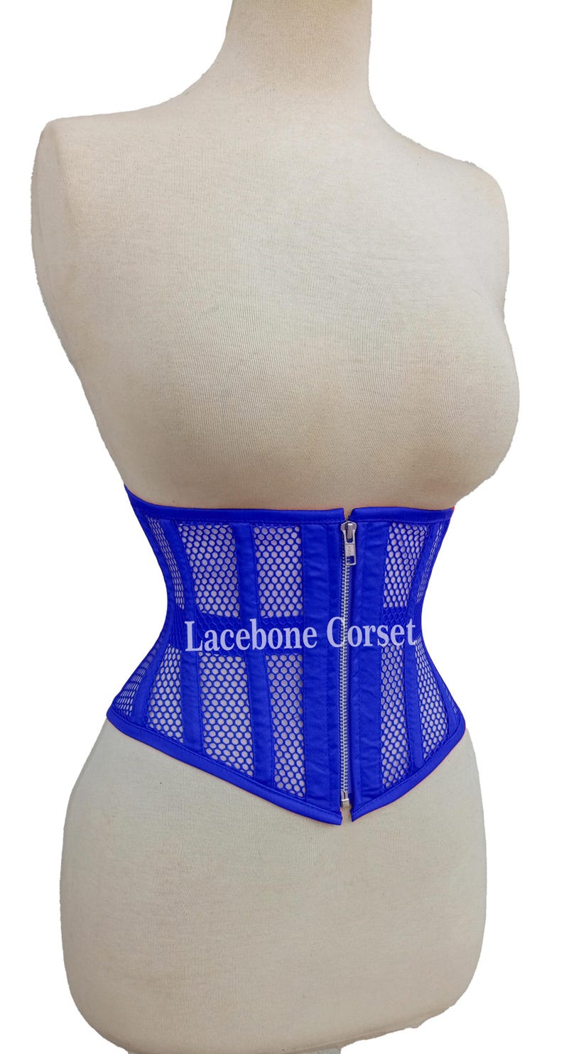 May include: A royal blue corset with a mesh and vertical stripe design. The corset has a silver zipper closure and the text "Lacebone Corset" is visible on the front. The corset is displayed on a mannequin.
