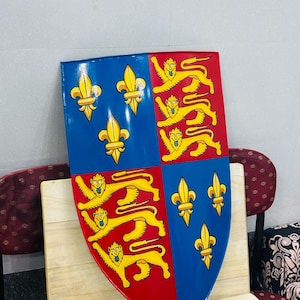 May include: A red and blue shield with a coat of arms. The shield is divided into four quarters. The top left and bottom right quarters are blue with three gold fleurs-de-lis. The top right and bottom left quarters are red with three gold lions.