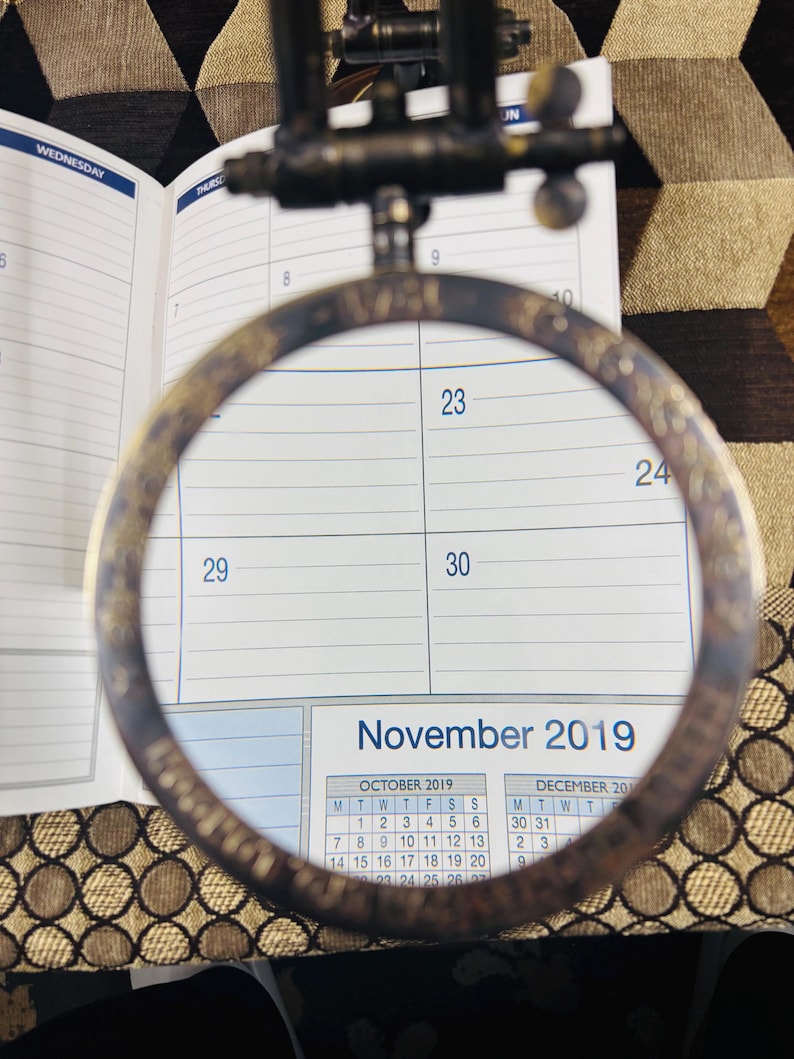 May include: A close-up of a calendar page with a magnifying glass over the dates 23, 24, 29, and 30. The calendar shows the months of October and December 2019, with November 2019 highlighted.