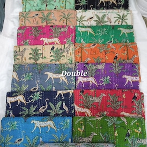 Peut inclure: Une pile de couettes doubles colorées avec divers motifs d'animaux et de plantes. Les motifs comprennent des zèbres, des léopards, des oiseaux et des palmiers. Les couettes sont dans des tons de bleu, vert, rose, orange et violet.