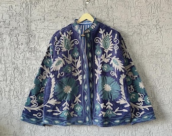 May include: A blue jacket with intricate floral embroidery in shades of teal and white. The jacket has a mandarin collar and a button-up front. The embroidery creates a detailed pattern across the jacket's surface.