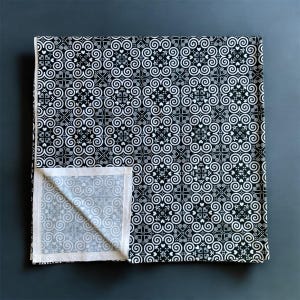 May include: Black and white fabric with a repeating pattern of swirls and hearts. The fabric is folded in half, showing the white underside.