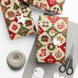 May include: Two rectangular gifts wrapped in paper with a diamond-patterned Christmas motif featuring Santa, ornaments, stockings, and pinecones. Each gift is tied with twine and a white star or heart-shaped tag, accompanied by a ball of twine and scissors.