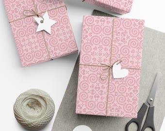 May include: Three pink gift boxes with a swirl pattern and white heart and star embellishments. The boxes are wrapped with twine and tied with bows. The boxes are on a light gray surface.