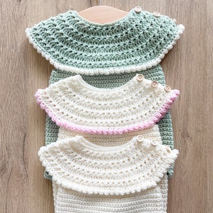 May include: Three crocheted collars in different colors, green, pink, and white, with wooden buttons. The collars are stacked on top of each other and hanging on a wooden hanger.