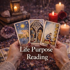May include: Three tarot cards with colorful illustrations are held in front of a blurred background of candles, books, and crystals. The cards feature figures and symbols. The text "Life Purpose Reading" is displayed below the cards.